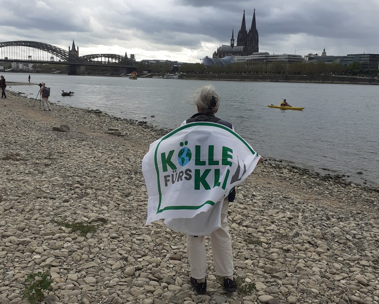Mensch steht am ausgetrockneten Rheinufer auf Höhe des Kölner Doms.