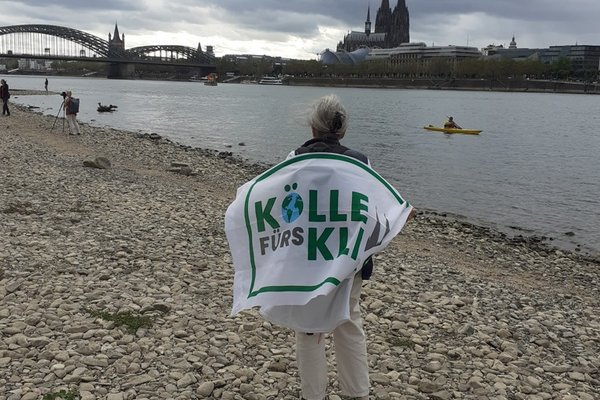 Mensch steht am ausgetrockneten Rheinufer auf Höhe des Kölner Doms.